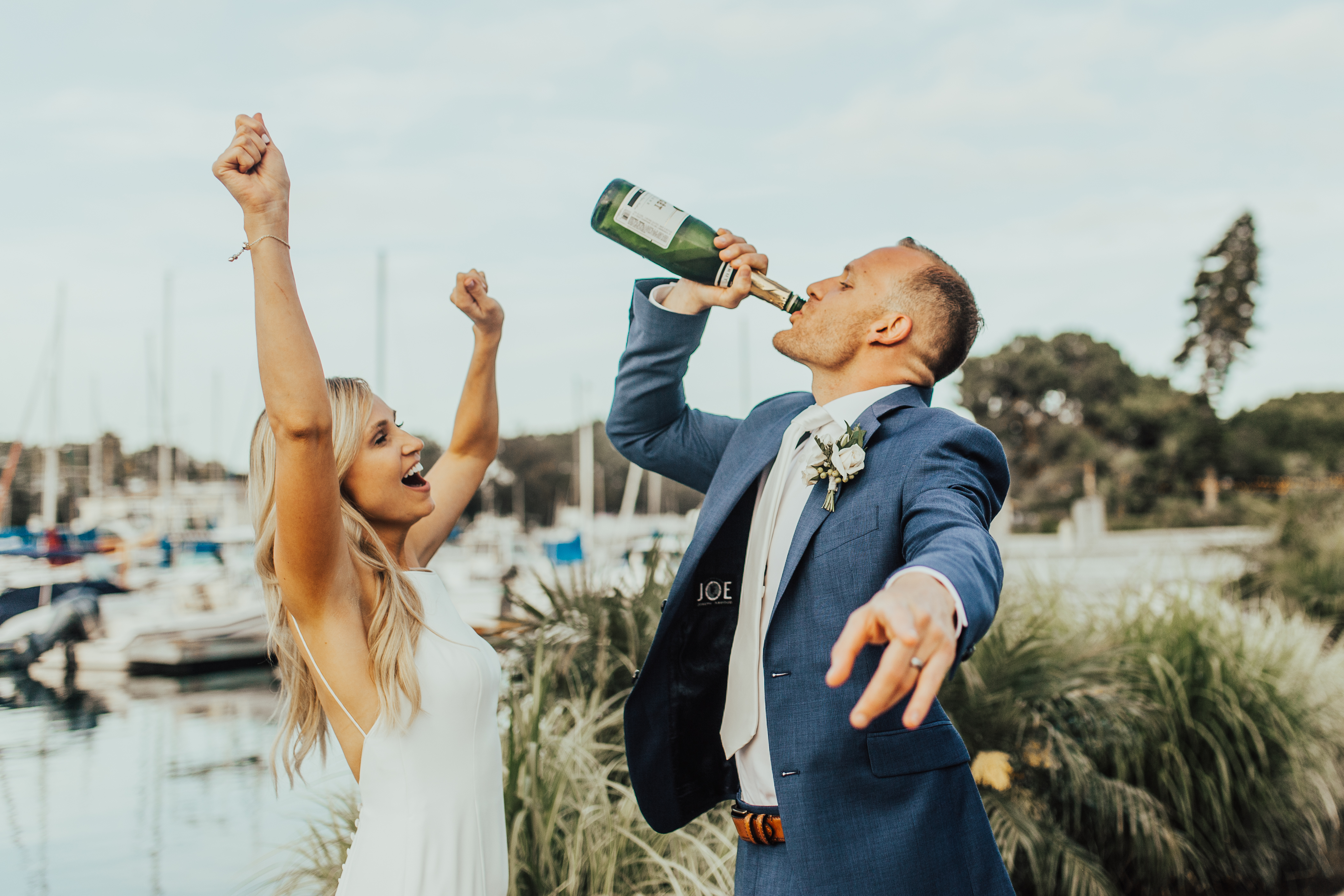 bride and groom drink from champagne bottle
